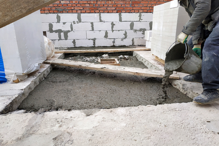 The builder pours a cement mortar slab between the floors of the house using a bucketの写真素材