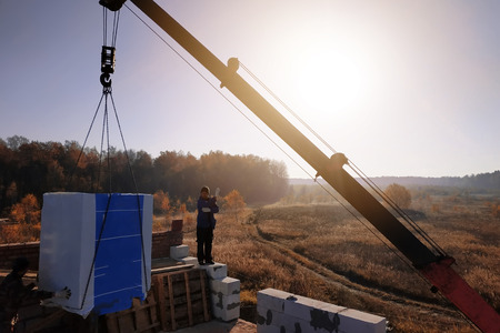 the employee controls the unloading of blocks for the construction of a house at the time farmの写真素材