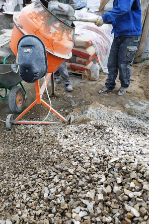 auxiliary worker develops a cement mortar in a concrete mixer at the construction of a country houseの写真素材