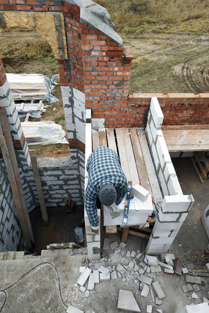 The master, using a trowel, glues gasblocks with a glutinous solution at the construction site 2018の写真素材