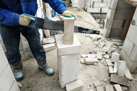 the worker cuts the gas unit with a hand saw at the construction site 2018の写真素材