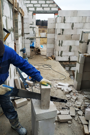 the worker cuts the gas unit with a hand saw at the construction site 2018の写真素材