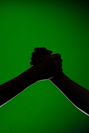 Two hands handshake, isolated on a green background, symbolizing friendship and reconciliation 2019の写真素材