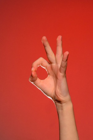 The human hand shows the sign ok symbolizing the positive, isolated on a red background 2019の写真素材