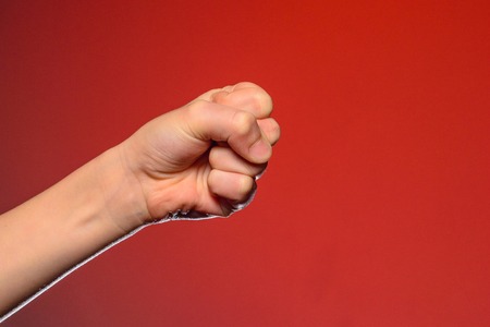 Human hand that squeezed fingers into a fist, symbolizing hatred and resistance, isolated on a red background 2019の写真素材