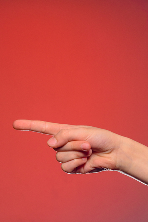 Human hand, showing an index finger on an object isolated on a red background 2019