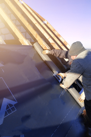 The worker stapler attaches to the rafter gidrobarierの写真素材