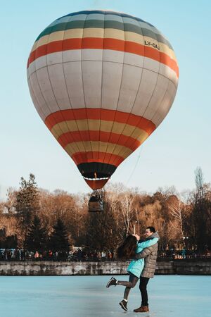 A young girl with a boy standing on the ice against the background of a balloon in the park. 2019