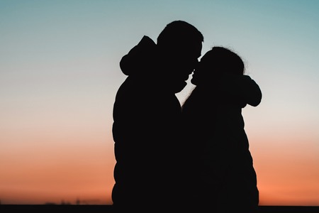 Silhouette of a lovely couple against the background of the lake and evening sky in the park. 2019の写真素材