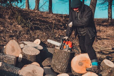 A young woman launches a chainsaw for cutting wood in the countryside 2019