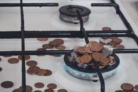 Blue flames of natural gas burning from a gas stove on a background of the coins.