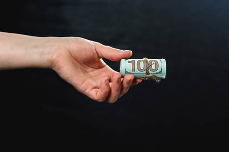 A woman's hand holding 100 hundred banknotes, a money transfer, a dark background. 2019の写真素材