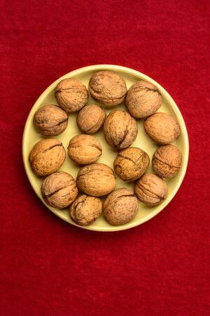 Walnuts in a plate on a red background. 2019の写真素材