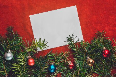Piece of paper for Christmas wishes on a red background with branches of Christmas tree and Christmas balls. 2019の写真素材