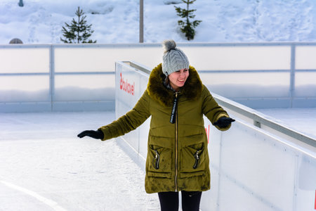 Bukovel, Ukraine February 12, 2019 - girl in green jacket skates on ice. 2019のeditorial素材