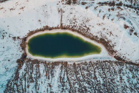 Beautiful couple walking in the phosphate-gypsum white mountains of Ukraine, the girl in a red dress on a background of a green lake. 2019の写真素材