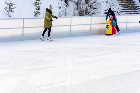 Bukovel, Ukraine February 12, 2019 - girl in green jacket skates on ice. 2019のeditorial素材