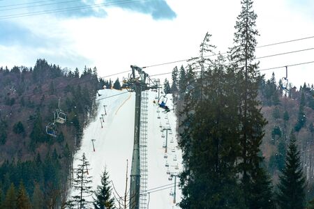 Ski slope with lift on the background of evergreen Carpathian forest, Bukovel resort, Carpathians,...