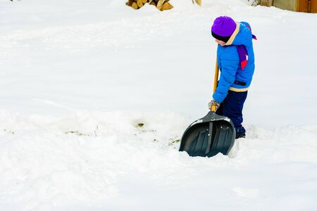Little boy with big shovel removes snow after a snowstorm. 2019の写真素材