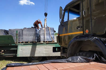 Workers unload pallets with bricks by means of the crane of automobile. 2019の写真素材