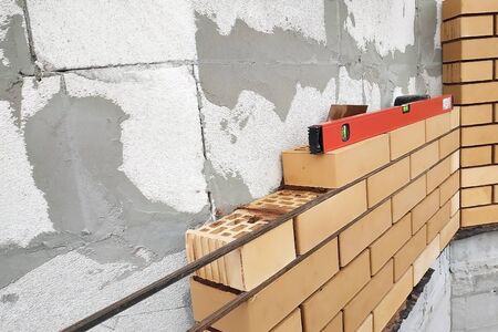 The master after laying the level to the brick, looks at the level horizontally.