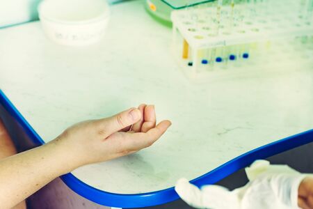 Closeup of blood sampling from finger, lab technician and patient hands.の写真素材