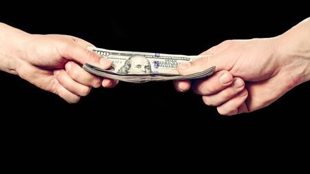Close up of a businessman's hands holding money over a black background. 2019