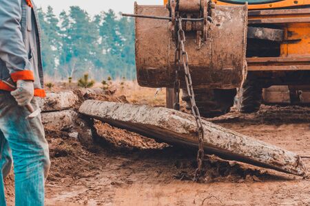 The worker unlocks the chains from the concrete slabs that the excavator carried with his bucket. 2019の写真素材