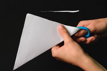 A boy on a black desk works with white paper. 2019