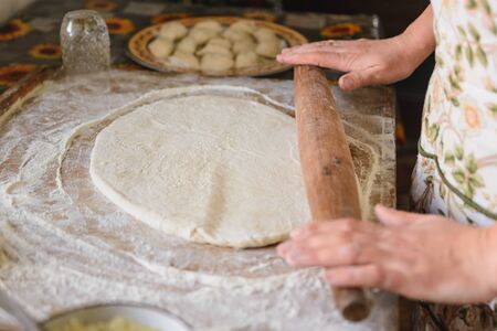 A woman at home rolls out dough for dumplings.2020