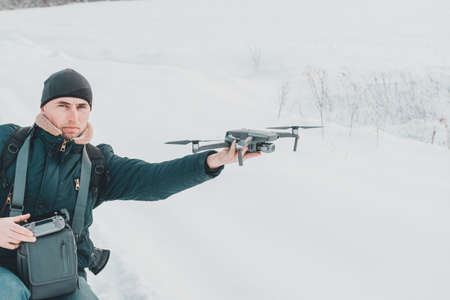 A young man launches a drone into the air in winter in the forest. 2020