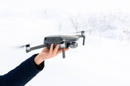 A young man launches a drone into the air in winter in the forest. 2020