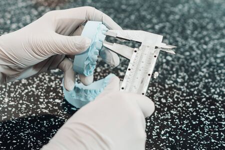 Orthodontic doctor measures caliper teeth on artificial human jaw from gypsum base 2020の写真素材