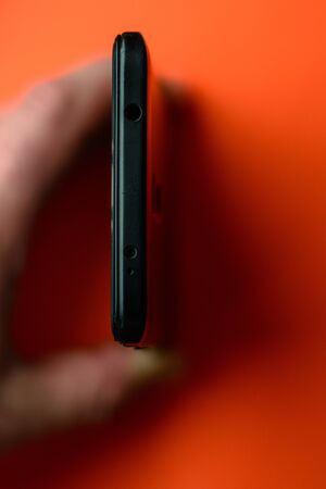 Man's hand holds smartphone and shows its side parts. 2020