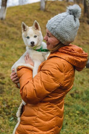 A woman loves and holds a brown and gray husky puppy in her arms. 2019の写真素材