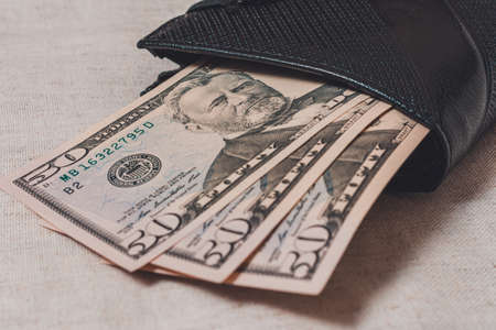 Black wallet with dollars 50 on a gray background.2020