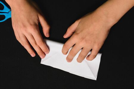 A boy on a black desk works with white paper. 2019の写真素材