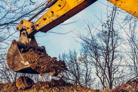 Backdrop of excavator bucket with soil on forest and sky background.2020の写真素材