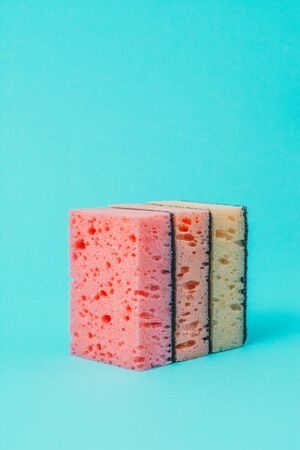 On a blue background, colored dishwashing sponges are arranged in steps