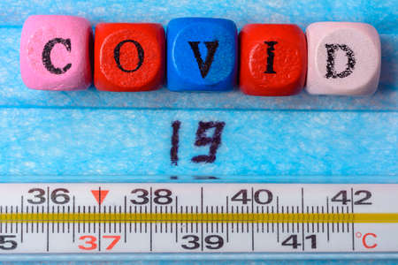 inscription coronavirus on mask background and high temperature thermometer.2020の写真素材