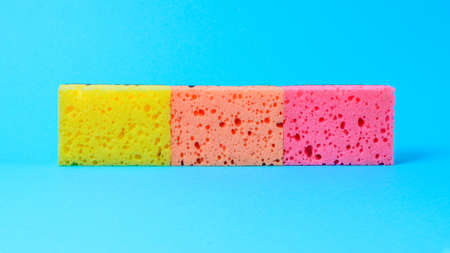 Colored dishes for washing dishes set in a row on a blue background.2020の写真素材