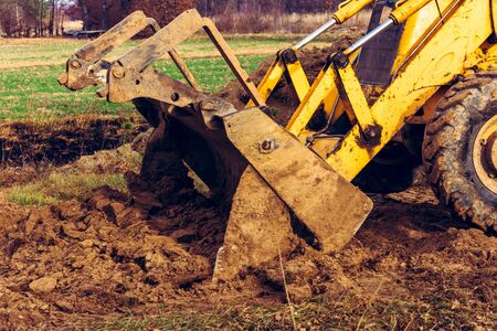 The excavator is digging the ground for the foundation and construction of a new road in the...