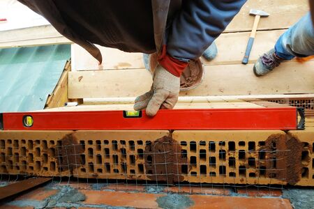 The worker puts the level on the silicate facade brick.2020