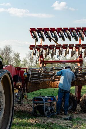 The farmer repairs the harrows if they are damaged by hitting stones. A master welder welds metal parts of agricultural equipment 2021.の写真素材