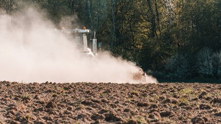 In the spring, a farmer pulls harrows with a modern tractor and sows a field with beets. Sowing...