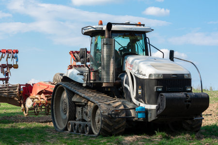 A very large white crawler tractor challenger stands in a field in summer while cultivating agricultural new land. Trostyanecz, Ukraine - April 29 2020.のeditorial素材