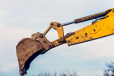 A close-up excavator loads soil into the bucket for further road installation. 2019の写真素材