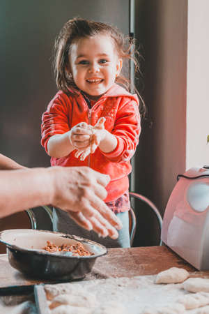 At home, granddaughter and grandmother cook dumplings in the kitchen. nachika from meat, the granddaughter is happy that her grandmother teaches.の写真素材