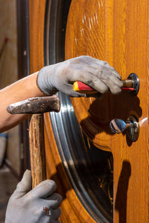 The master worker installs a door lock in the front door, metal doors with a polymer coating. 2020
