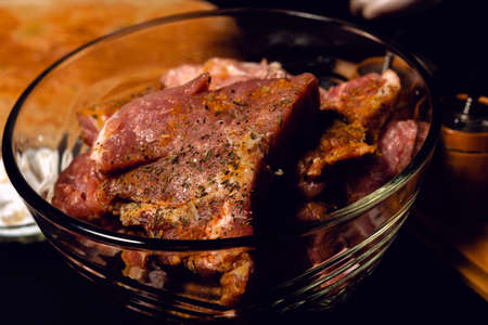 The chef in white gloves rubs pieces of pork with spices, uses curry, basil and salt, marinates the meat on a barbecue. 2020の写真素材